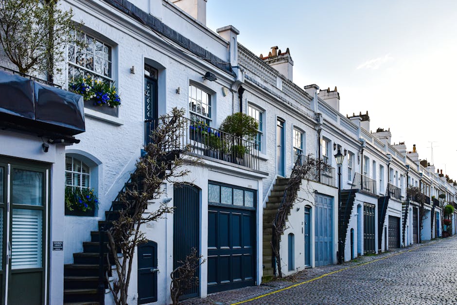 A row of elegant Victorian-style terraced houses with white facades, decorative mouldings, and large sash windows, located along a street in Belgravia. The buildings feature prominent brick and stucco